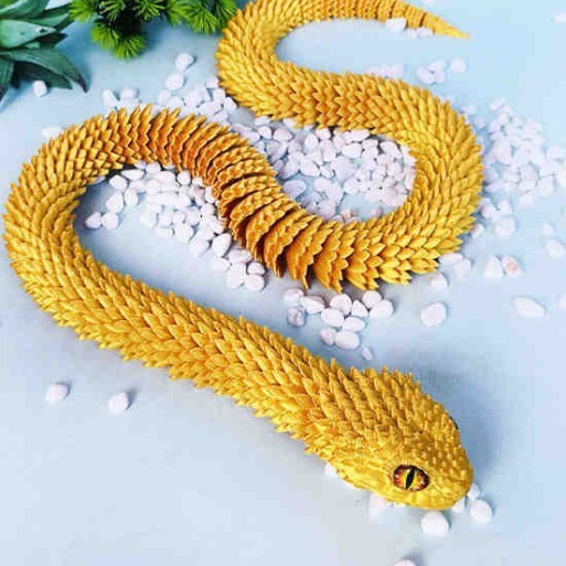 3D printed golden snake toy decoration on stones.