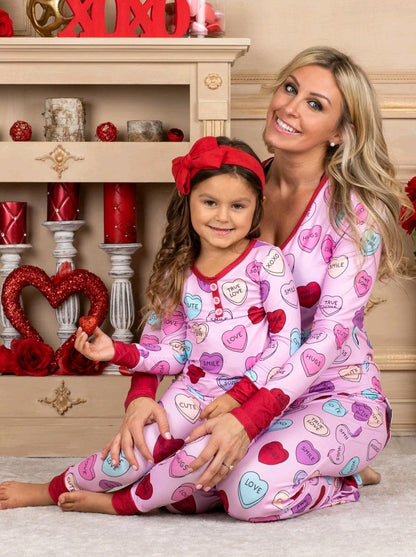 Family in heart print matching pyjamas for Valentine's Day, soft cotton blend.