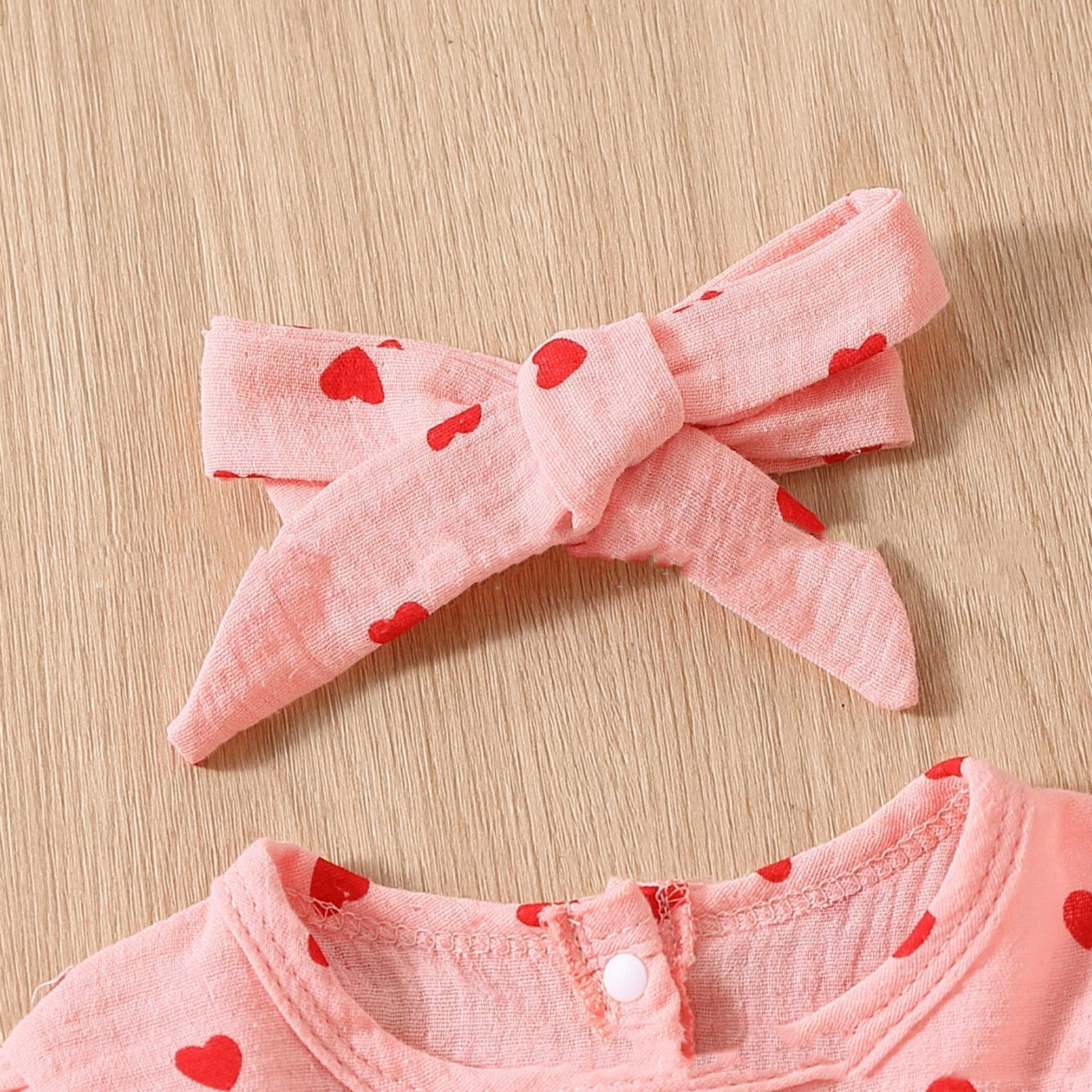 Adorable baby girl Valentine's Day dress with pink heart pattern and matching bow.