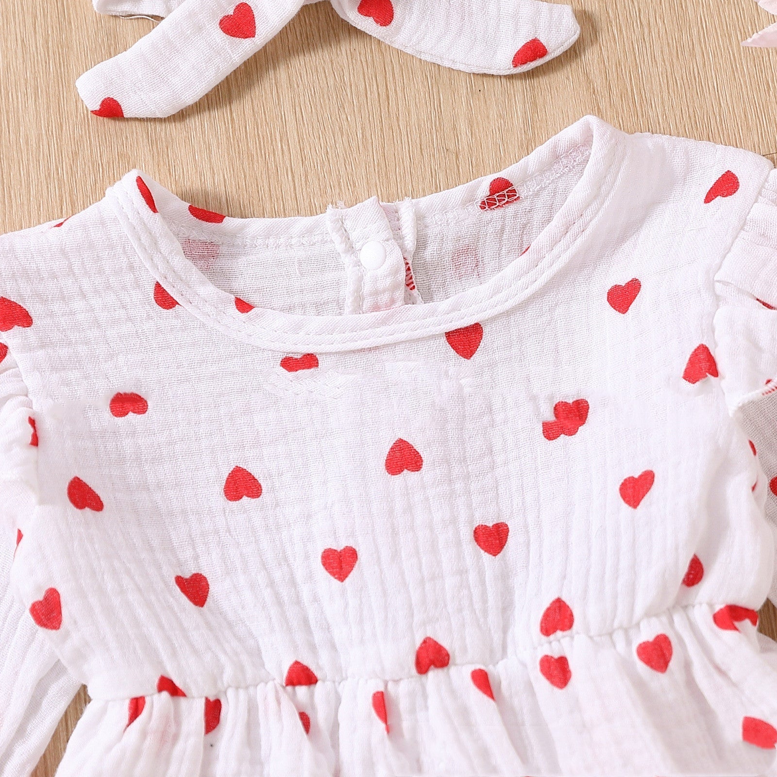 Adorable baby girl Valentine's Day dress with red heart pattern, long sleeves, and soft cotton fabric.
